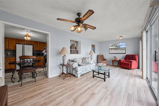 living room featuring a textured ceiling, ceiling fan, and light hardwood / wood-style floors