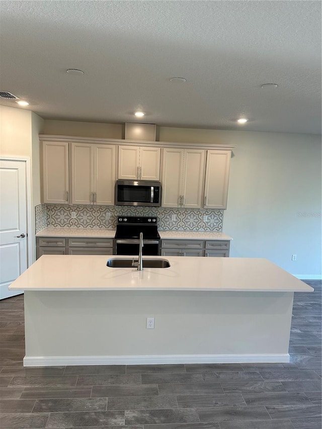 kitchen with sink, decorative backsplash, a center island with sink, electric range, and dark wood-type flooring