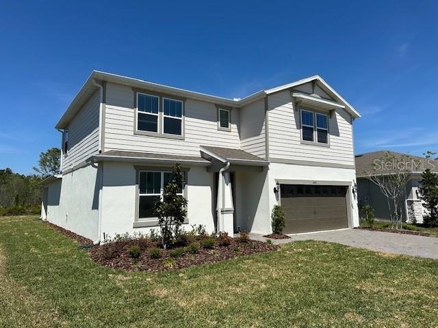 5425 Log Grove Ln, Orlando, FL 32829 - view of front of home featuring stucco siding, an attached garage, a front yard, and driveway