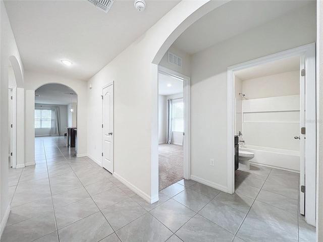 hallway featuring light tile patterned flooring and plenty of natural light