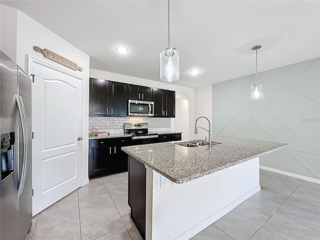 kitchen featuring stainless steel appliances, sink, hanging light fixtures, and an island with sink