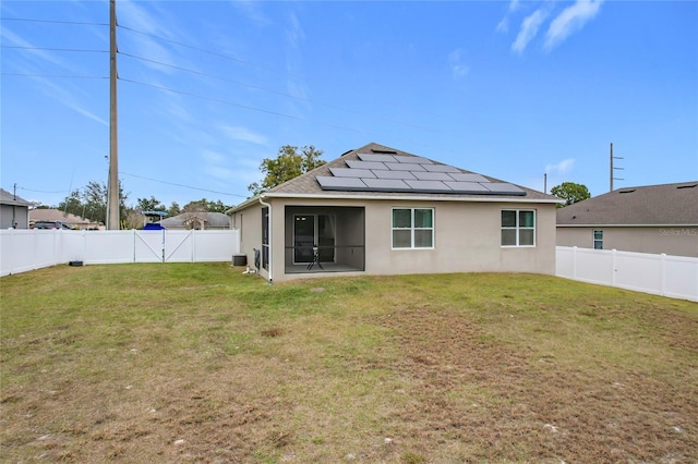 back of house featuring solar panels and a lawn