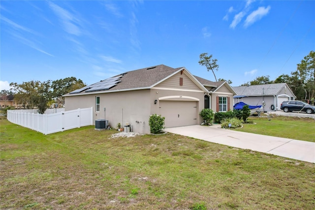 view of front of property featuring a front yard, a garage, cooling unit, and solar panels