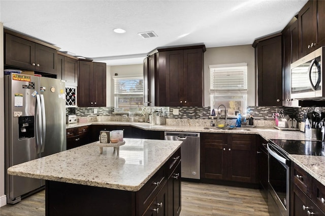 kitchen featuring sink, stainless steel appliances, light hardwood / wood-style flooring, and a center island