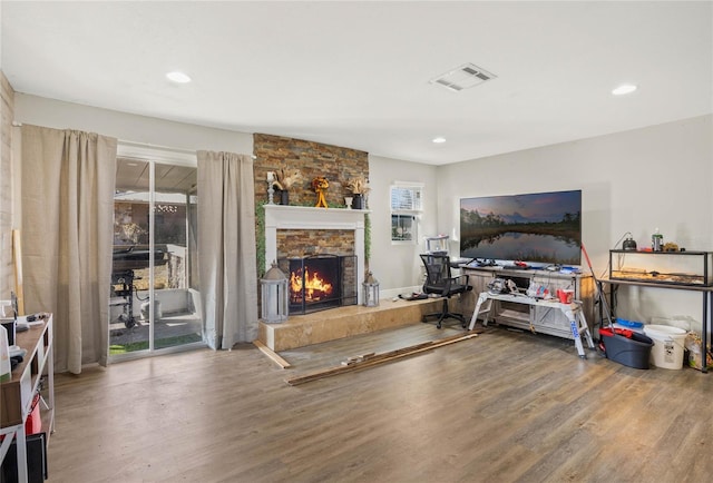 living room with wood-type flooring and a stone fireplace