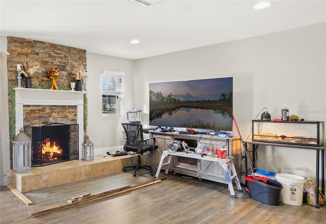 office with hardwood / wood-style flooring and a stone fireplace