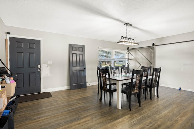 dining room featuring dark hardwood / wood-style flooring, a textured ceiling, and a barn door