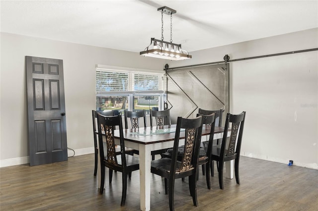 dining area with dark hardwood / wood-style flooring and a barn door