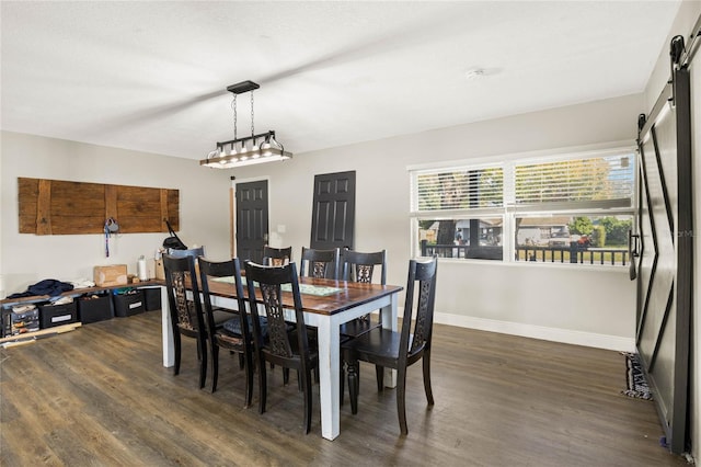 dining area with dark hardwood / wood-style flooring and a barn door