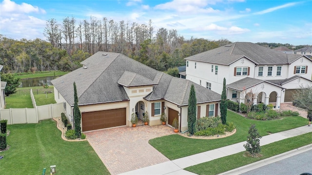 view of front of home with a front lawn, a garage, and a water view