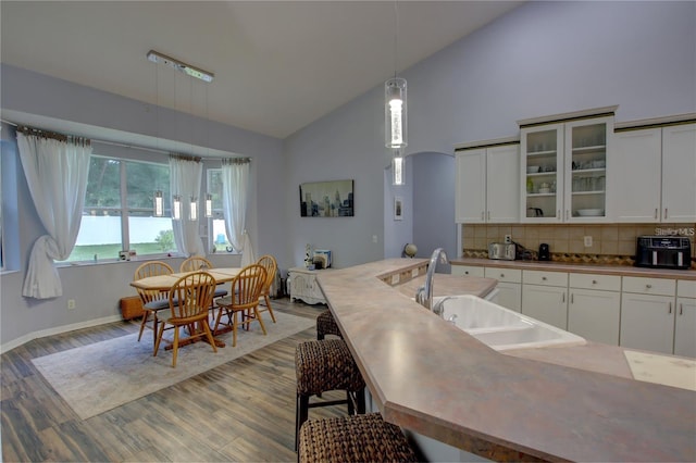 kitchen featuring decorative light fixtures, white cabinetry, backsplash, and sink