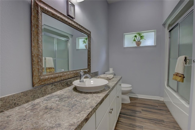 full bathroom with toilet, wood-type flooring, vanity, and shower / bath combination with glass door