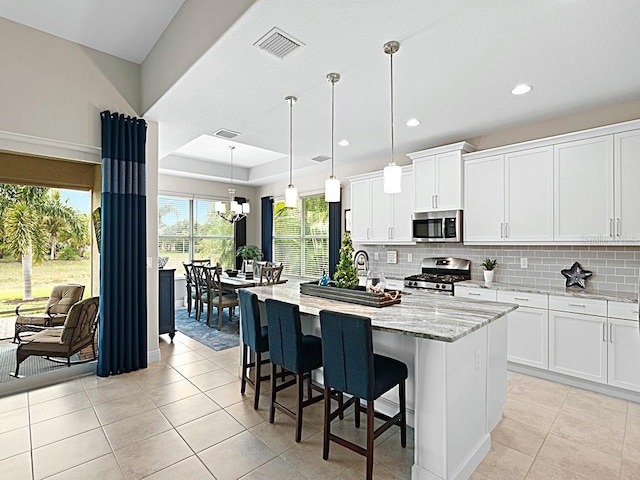 kitchen with white cabinetry, appliances with stainless steel finishes, an island with sink, and hanging light fixtures