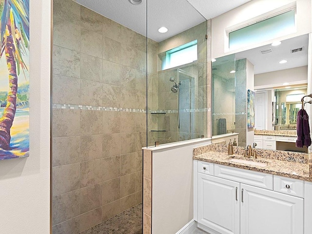 bathroom with a tile shower and vanity