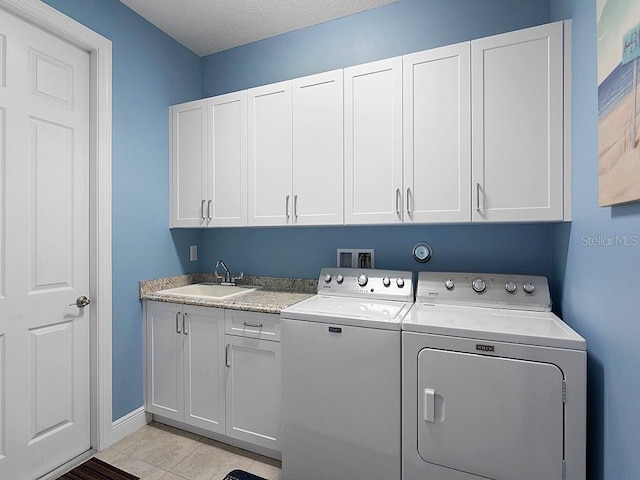 laundry area featuring sink, cabinets, a textured ceiling, light tile patterned floors, and washer and clothes dryer