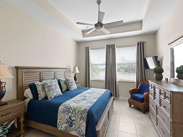 tiled bedroom with a raised ceiling, a textured ceiling, and ceiling fan