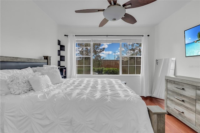 bedroom featuring ceiling fan, multiple windows, and hardwood / wood-style flooring