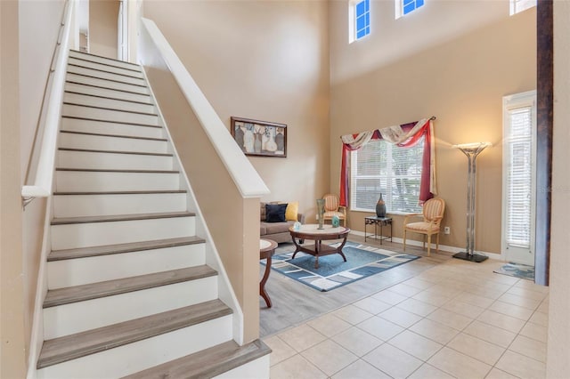 staircase featuring a towering ceiling and tile patterned floors