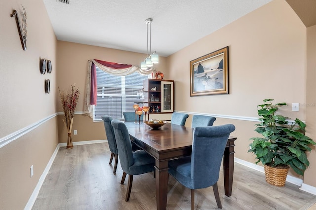 dining area with light wood-type flooring and a textured ceiling