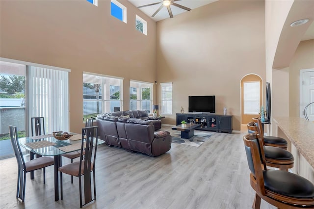 living room featuring a towering ceiling, ceiling fan, and light hardwood / wood-style floors