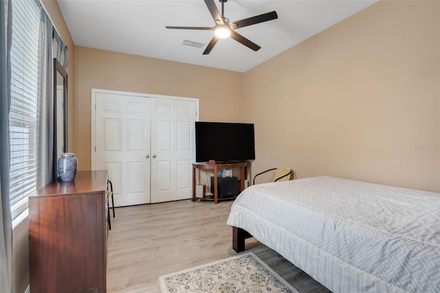 bedroom with light wood-type flooring, ceiling fan, and a closet