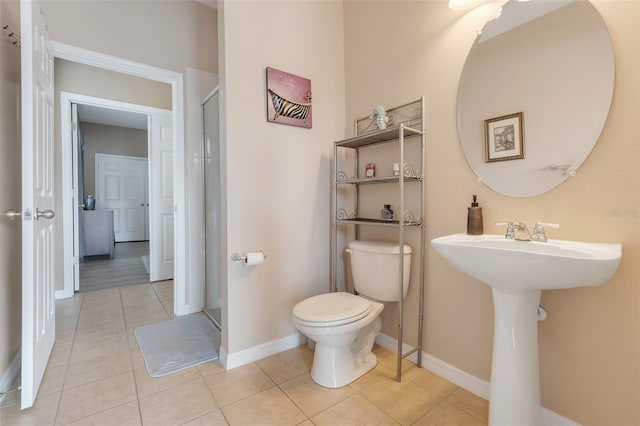 bathroom featuring toilet, a shower with door, and tile patterned floors