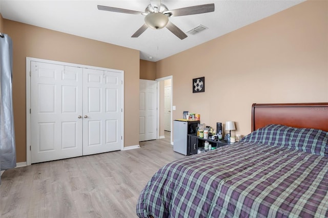 bedroom featuring ceiling fan, light hardwood / wood-style floors, refrigerator, and a closet