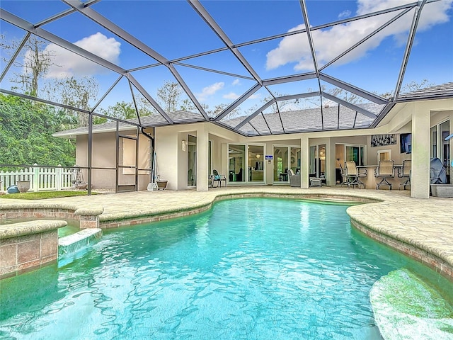 view of pool featuring glass enclosure, an outdoor bar, and a patio