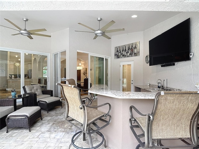 view of patio with ceiling fan, a bar, and an outdoor living space