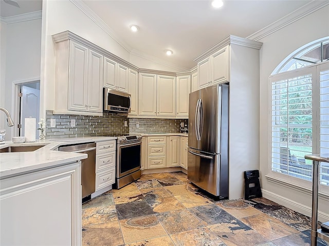 kitchen featuring appliances with stainless steel finishes, a healthy amount of sunlight, tasteful backsplash, sink, and light stone counters