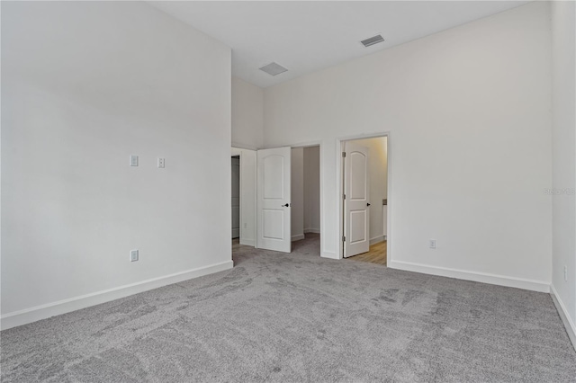 unfurnished bedroom with light colored carpet and a towering ceiling