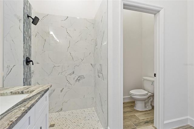 bathroom with a tile shower, vanity, and toilet