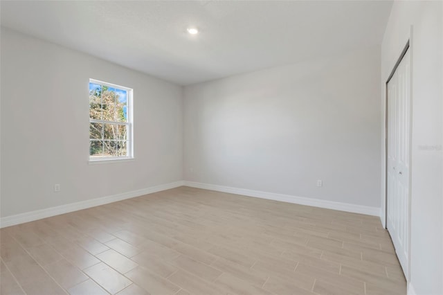 unfurnished bedroom featuring recessed lighting, a closet, light wood-style flooring, and baseboards