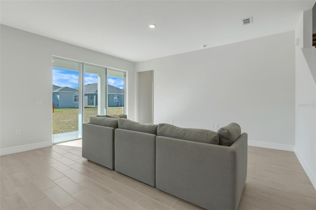 living room featuring light wood finished floors, baseboards, and visible vents