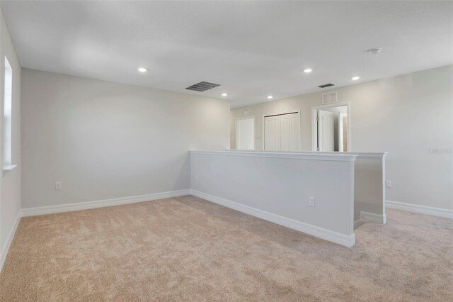 unfurnished room featuring recessed lighting, light carpet, visible vents, and baseboards