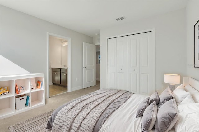 bedroom with a closet, visible vents, light carpet, ensuite bath, and baseboards