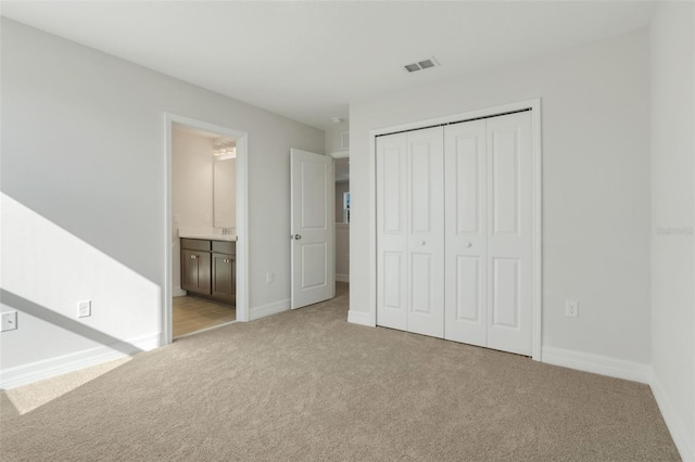 unfurnished bedroom featuring baseboards, visible vents, a closet, and light colored carpet