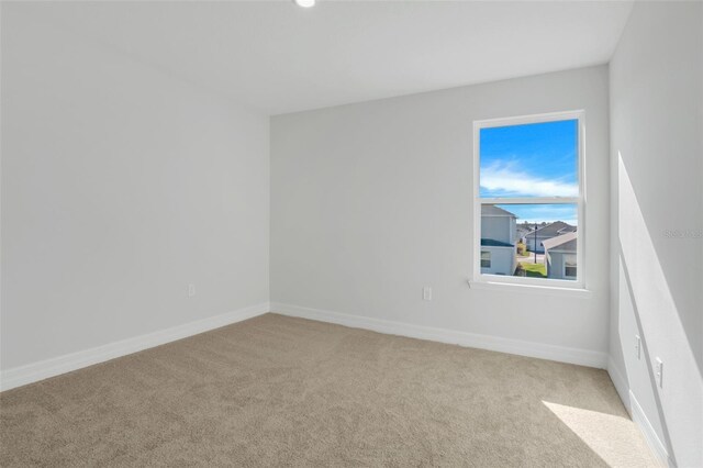 empty room featuring light carpet and baseboards