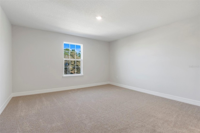 empty room featuring a textured ceiling, carpet flooring, and baseboards