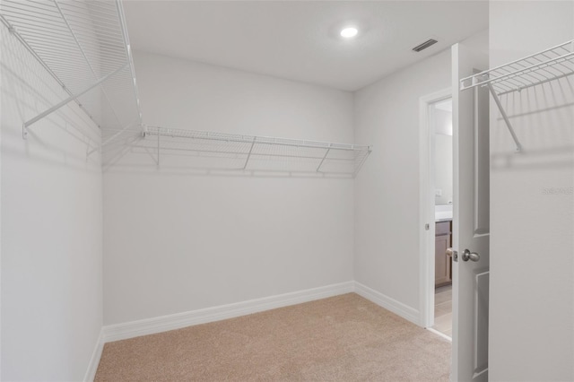 spacious closet with light colored carpet and visible vents