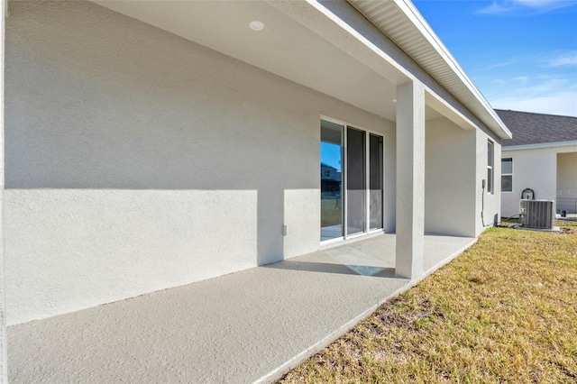 exterior space featuring stucco siding, a yard, central AC unit, and a patio