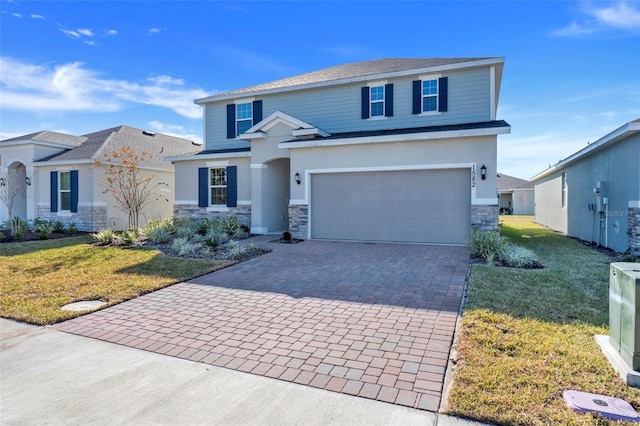 view of front of home featuring a garage, stone siding, a front lawn, and decorative driveway