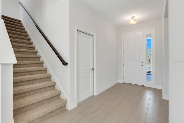 entryway featuring light wood-style floors, stairway, and baseboards