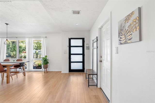 foyer entrance featuring a textured ceiling and light hardwood / wood-style floors