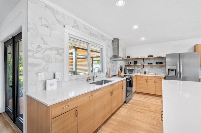 kitchen featuring sink, wall chimney range hood, light wood-type flooring, and appliances with stainless steel finishes