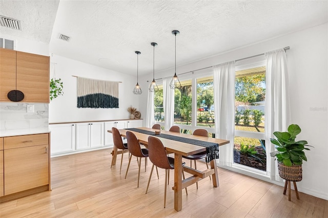 dining area featuring light wood-type flooring and a textured ceiling