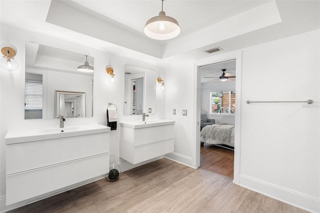 bathroom featuring ceiling fan, a raised ceiling, vanity, and wood-type flooring