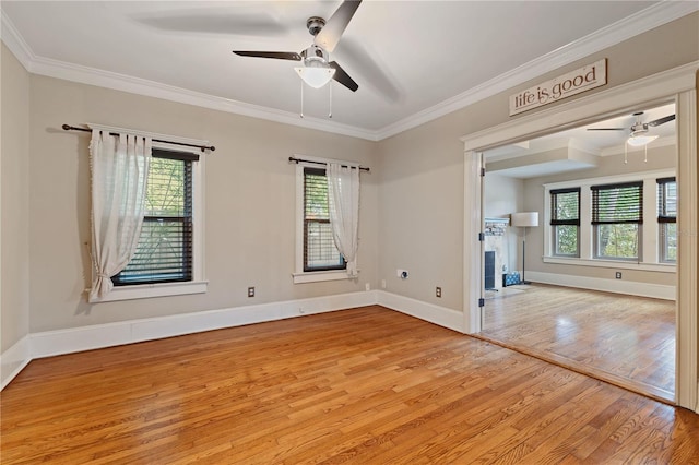 empty room featuring ceiling fan, a wealth of natural light, crown molding, and light hardwood / wood-style flooring