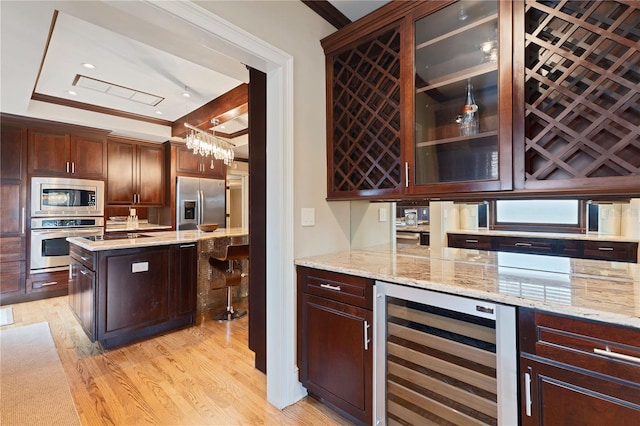 kitchen featuring light hardwood / wood-style floors, stainless steel appliances, wine cooler, hanging light fixtures, and ornamental molding