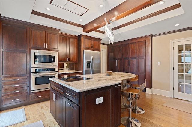 kitchen with pendant lighting, appliances with stainless steel finishes, a kitchen island, light hardwood / wood-style floors, and light stone counters